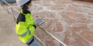 Environmental engineer with hard hat and iPad at a wastewater treatment plant