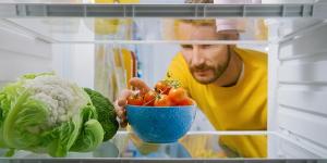 Man taking bowl of tomatoes out from refrigerator