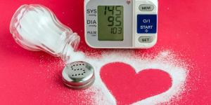 Spilled salt forms the shape of a heart while shown next to a blood pressure monitor.