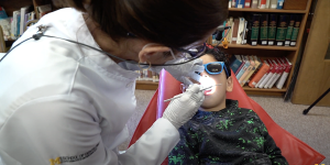 A clinical trial participant receives an oral exam at school from a dental clinician on the study.