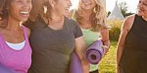 Group of women laughing and holding yoga mats
