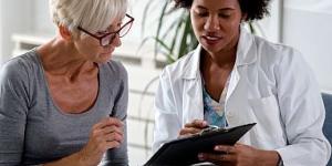 Female doctor speaking with an elderly female patient while looking at test results.